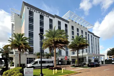 a hotel with palm trees in front of a building at Hotel Dello Ft Lauderdale Airport, Tapestry Collection by Hilton in Dania Beach