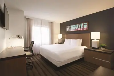 a hotel room with a white bed and a desk at Hyatt House Miami Airport in Miami