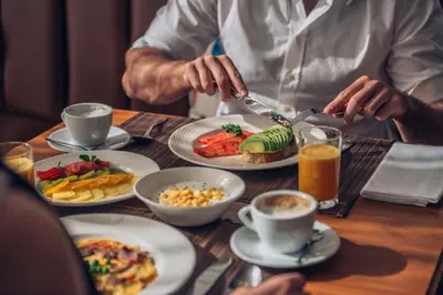 a man eating food on a table with plates of food at Iberostar Waves Berkeley Shore in Miami Beach