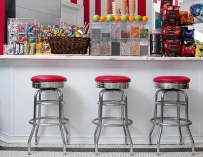 two bar stools with red tops sitting at a counter at Pelican Grand Beach Resort, a Noble House Resort in Fort Lauderdale