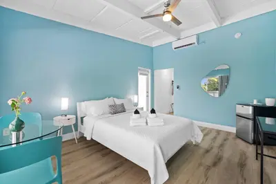 a blue bedroom with a white bed and a table at The New Yorker Hotel Miami in Miami