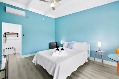 a blue bedroom with a white bed and a table at The New Yorker Hotel Miami in Miami