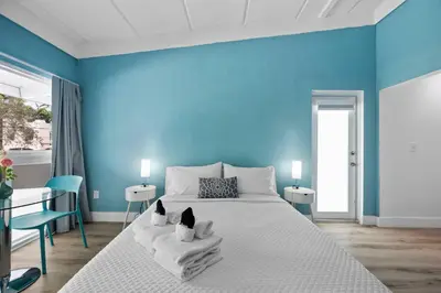 a blue bedroom with a bed with two cats sitting on towels at The New Yorker Hotel Miami in Miami