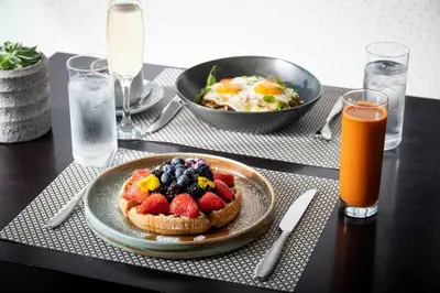 a table with a plate of food with fruit on it at Kimpton EPIC Hotel by IHG in Miami