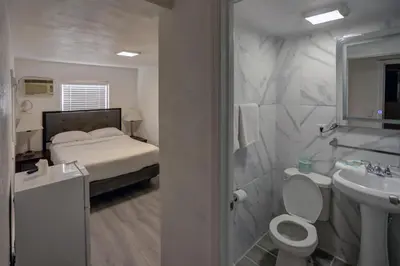 a bathroom with a bed and a toilet and a sink at Beach and Town Motel in Hollywood