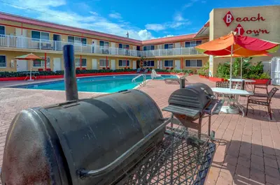 a hotel with a pool and a grill next to a resort at Beach and Town Motel in Hollywood