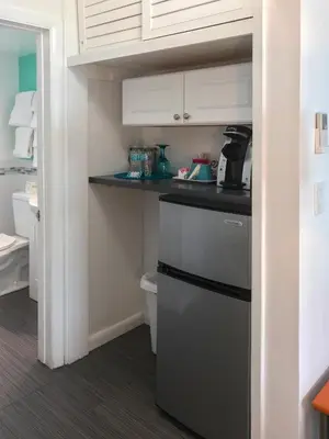 a small kitchen with a black refrigerator and white cabinets at Nobleton Hotel in Fort Lauderdale