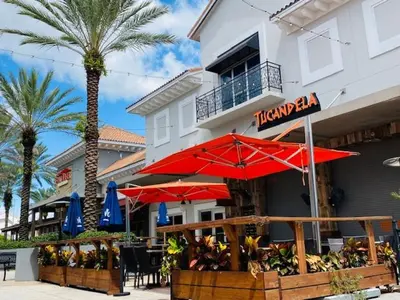 a restaurant with red umbrellas in front of a building at The Palms Inn & Suites Miami, Kendall, FL in Kendall