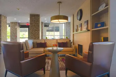 a living room with a couch and a table and chairs at The Palms Inn & Suites Miami, Kendall, FL in Kendall
