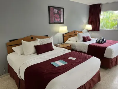 a hotel room with two beds with red and white sheets at The Grand Resort and Spa & Worthington All Male in Fort Lauderdale