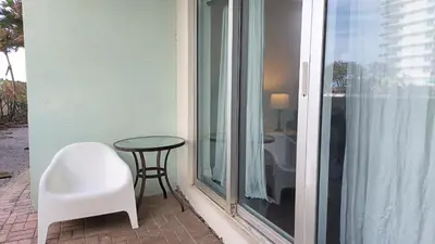 a white chair and a table and a glass window at The Tides-1 bedroom apartment Ground Floor in Hollywood