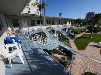 a balcony of a house with blue stairs and chairs at Holiday Isle Yacht Club in Fort Lauderdale