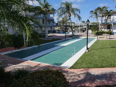 a tennis court in front of a building with palm trees at Holiday Isle Yacht Club in Fort Lauderdale