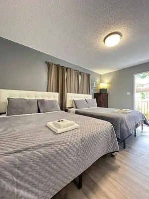 a bedroom with two beds and a window at Sheridan Guesthouse in Dania Beach