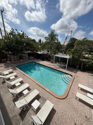 a swimming pool with chaises and lounge chairs next to it at Sheridan Guesthouse in Dania Beach