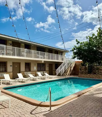 a swimming pool in front of a building with chairs at Sheridan Guesthouse in Dania Beach