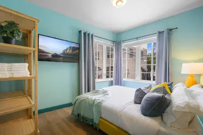 a bedroom with a bed with blue walls and a window at Barbizon on Ocean Drive Apartments in Miami Beach