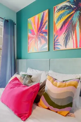 a bedroom with a bed with colorful pillows and paintings at Barbizon on Ocean Drive Apartments in Miami Beach