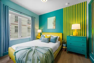 a blue bedroom with a bed and a window at Barbizon on Ocean Drive Apartments in Miami Beach