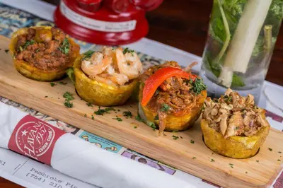 a wooden tray with four muffins with meat and vegetables at Hotel Breakwater South Beach in Miami Beach