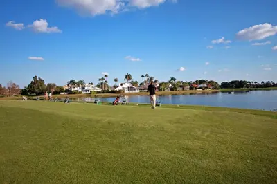 a man walking on the grass next to a lake at Grand Palms Spa & Golf Resort in Pembroke Pines