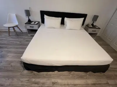 a bed in a room with two tables and a chair at Grand Palms Spa & Golf Resort in Pembroke Pines