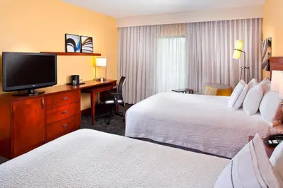 a hotel room with two beds and a desk with a television at Courtyard Miami Airport West Doral in Miami