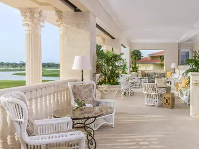 a porch with white chairs and tables and a view of the golf course at Trump National Doral Golf Resort in Miami