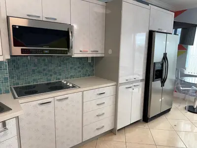 a kitchen with white cabinets and a stainless steel refrigerator at Ocean Front Units at Miami Beach in Miami Beach