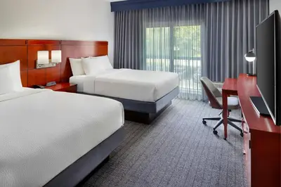 a hotel room with two beds and a desk and a television at Courtyard by Marriott Fort Lauderdale City of Plantation in Plantation