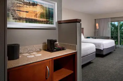 a hotel room with a bedroom with a bed and a desk at Courtyard by Marriott Fort Lauderdale Airport & Cruise Port in Dania Beach