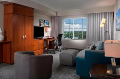 a hotel room with a desk and a living room at Courtyard by Marriott Fort Lauderdale Airport & Cruise Port in Dania Beach