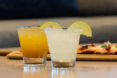 two cocktails sitting on a table with a slice of pizza at Courtyard by Marriott Fort Lauderdale Airport & Cruise Port in Dania Beach