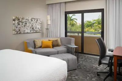 a hotel room with a bed and a couch and a chair at Sonesta Select Miami Lakes in Miami Lakes