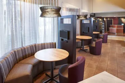 a waiting room with tables and chairs and windows at Sonesta Select Miami Lakes in Miami Lakes