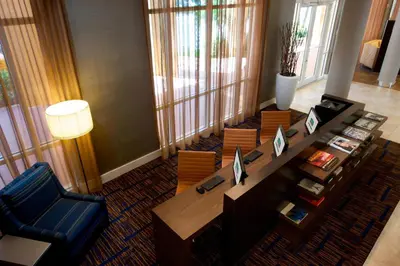 a living room with a desk and chairs and a table at Courtyard Miami Dadeland in Miami