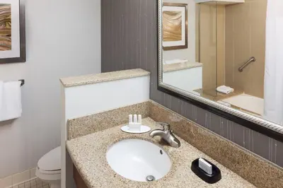 a bathroom with a sink and a toilet and a mirror at Courtyard by Marriott Miami at Dolphin Mall in Miami