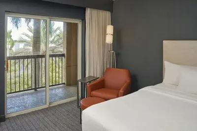 a hotel room with a bed and a chair and a window at Courtyard by Marriott Fort Lauderdale Weston in Weston