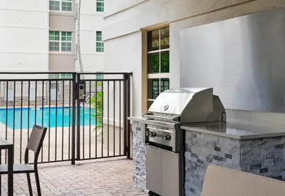 a grill on a patio with a view of a pool at Residence Inn Fort Lauderdale SW/Miramar in Miramar