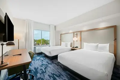 a hotel room with two beds and a desk at Fairfield Inn & Suites Fort Lauderdale Airport & Cruise Port in Dania Beach