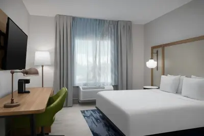 a bedroom with a white bed and a desk and a window at Fairfield Inn & Suites Fort Lauderdale Airport & Cruise Port in Dania Beach
