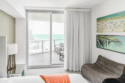a bedroom with a bed and a balcony with the ocean at Luxurious Hyde Resort Apartments in Hollywood