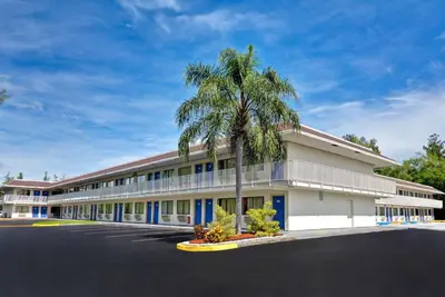 a large building with a palm tree in front of it at Motel 6 Dania Beach in Dania Beach