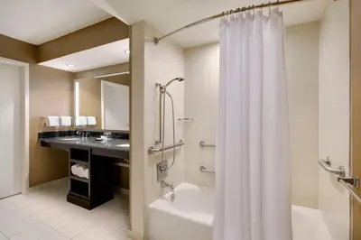 a bathroom with a tub and a shower curtain at Sheraton Suites Fort Lauderdale West in Plantation