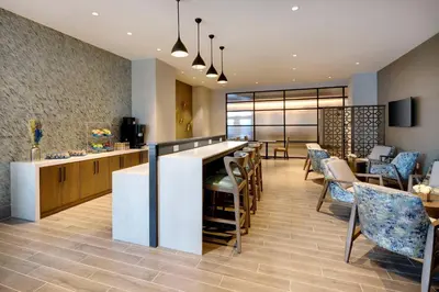 a lobby with a bar and chairs and a restaurant at Sheraton Suites Fort Lauderdale West in Plantation