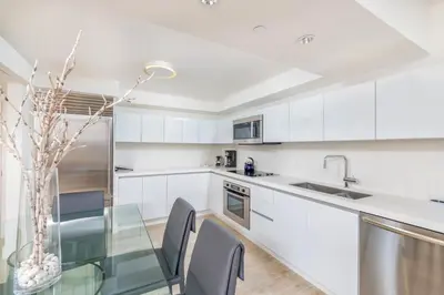 a kitchen with white cabinets and a glass table at Oceanfront Private Condo at 1 Hotel & Homes -1019 in Miami Beach