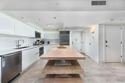 a kitchen with white cabinets and a wooden table at Oceanview Private Condo at 1 Hotel & Homes -1408 in Miami Beach