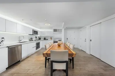 a kitchen with a wooden table and white cabinets at Oceanview Private Condo at 1 Hotel & Homes -1040 in Miami Beach