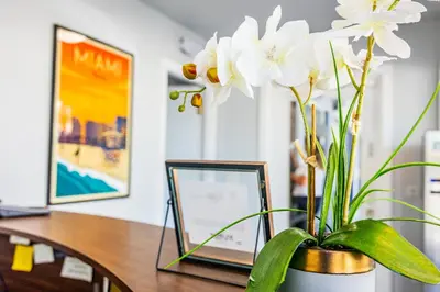 a desk with a vase with white flowers on it at Up Midtown in Miami