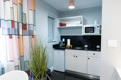 a kitchen with white cabinets and a microwave at The Cove By Renzzi in Miami Beach
